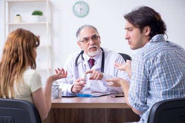 Young couple visiting old male doctor