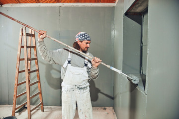 Painter painting walls with a extender roller indoors.
