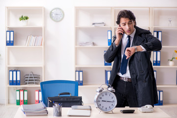 Young male employee in the office in time management concept
