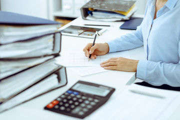 Unknown female bookkeeper or financial inspector calculating or checking balance, making report, close-up. Internal Revenue Service at work with financial document. Tax and audit concept