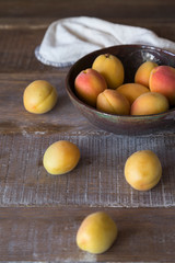 fresh apricots in the ceramic plate on the wooden background.