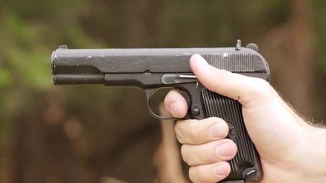 A man shoots a gun. Hand holding a gun close-up.