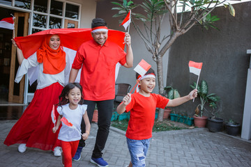 excited indonesia family with flag together in front of their house