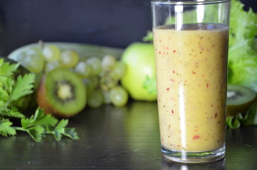 Health Drink and Smoothie Diet. Green fruits and vegetables on a black background. Kiwi, green grapes, lettuce, zucchini, cucumbers, green apple, parsley with spinach top view selective focus