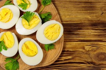 Boiled eggs with parsley on cutting board on a wooden table. Top view