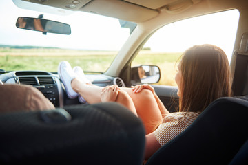 Woman holding her legs on dashboard in car