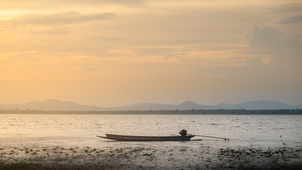Naklejka premium lonely fishing boat docked in calm lake. wooden fishing boat in a still lake water. image of wooden fishing boat moored on the shore