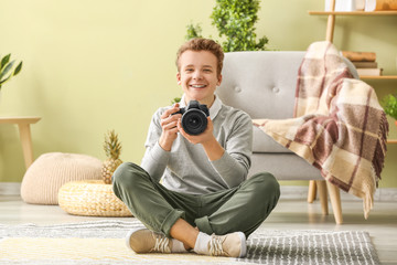 Teenage boy with photo camera at home