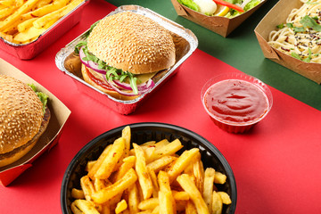 Containers with delicious food on color background