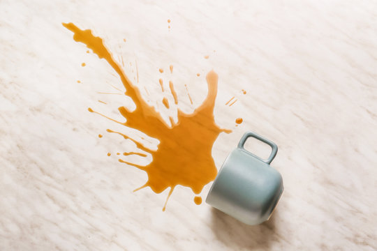 Cup with spilled drink on light background