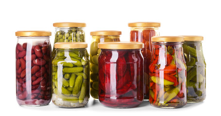 Jars with different canned vegetables and legumes on white background