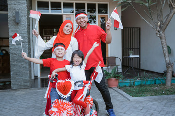 asian family with indonesia flag. indonesian independence day celebration with family at home. decorating bicycle