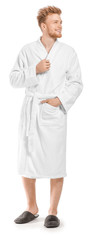 Handsome young man in bathrobe on white background