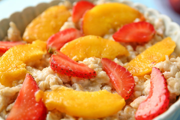 Bowl with tasty sweet oatmeal and fruits, closeup