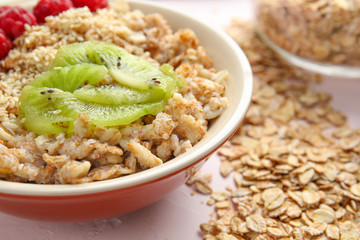Bowl with tasty sweet oatmeal on light background