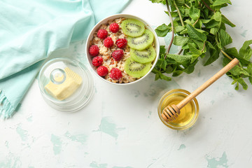 Bowl with tasty sweet oatmeal, butter and honey on light table