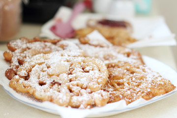 Homemade funnel cakes with powdered sugar on a ceramic plate.
