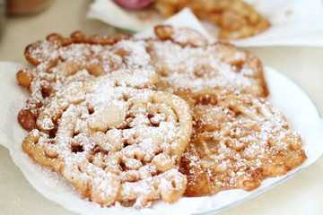 Homemade funnel cakes with powdered sugar on a ceramic plate.