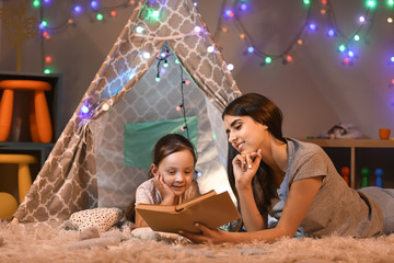 Mother and her little daughter reading book in evening © Pixel-Shot