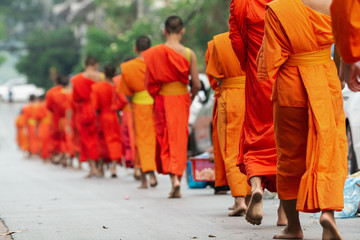 Laotian Buddhist monks walking along the street during alms giving ceremony in Luang Prabang, Laos