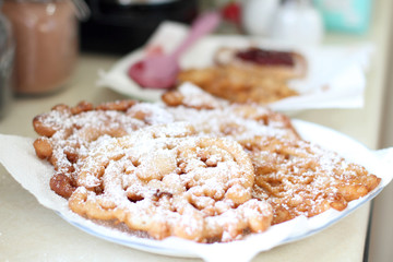 Homemade funnel cakes with powdered sugar on a ceramic plate.