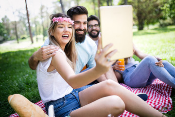 Happy friends in the park having picnic on a sunny day.