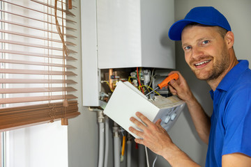 smiling maintenance and repair service engineer working with house gas heating boiler