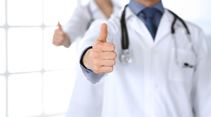 Group of doctors showing thumbs up. Perfect medical service in clinic. Happy future in medicine and healthcare concept