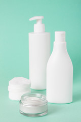 a large bottle of lotion and cream on a green background. vertical frame.