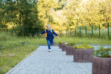 Fototapeta premium The pupil runs with a backpack to school. The concept of learning, school, mind, lifestyle and success.