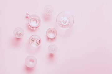 Many empty glasses on pink background. Top view, flat lay.