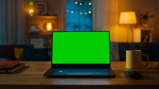 Laptop Computer Showing Green Chroma Key Screen Stands on a Desk in the  Living Room. In the Background Cozy Living Room in the Evening with Warm  Lights on. foto de Stock