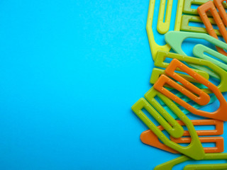 Multi-colored paper clips scattered over a turquoise background. View from above. The concept is time to school. space for text