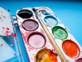 multicolored paint and brush on blue background