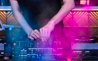 Hands of EDM DJ plays and controls the disc at the turntable. Party concept at the nightclub.