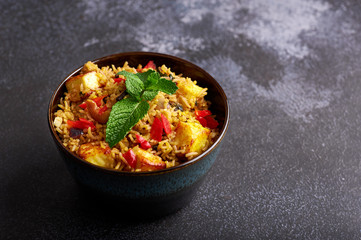 vegetarian paneer biryani at black background. paneer biryani is traditional veg indian cuisine dish with paneer cheese, basmati rice, masala, chili pepper, mint and many another spices. Copy space