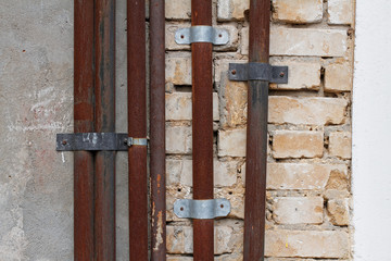 Old rusty metal pipes on brick and concrete wall background