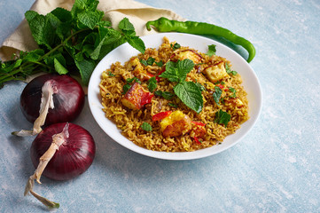 vegetarian paneer biryani at blue background. paneer biryani is traditional veg indian cuisine dish with paneer, basmati rice, masala, chili, mint. Copy space
