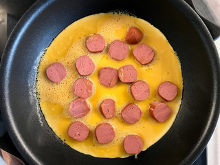 Raw Omelette in Pan with Sausage / Salami Slices.