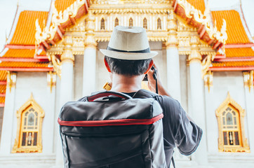 Obraz premium Asian man tourist taking photo with camera at Wat Benchamabophit Dusitvanaram Bangkok Thailand. Travelers take pictures with DSLR cameras. Asia tourist, Thailand. .