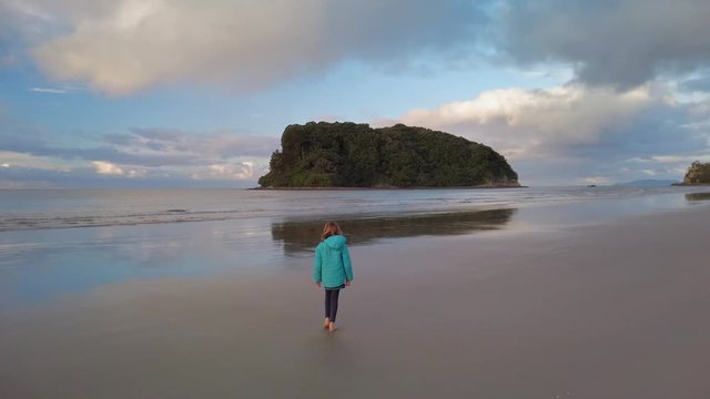 Young girl walking on the beach in winter, late afternoon