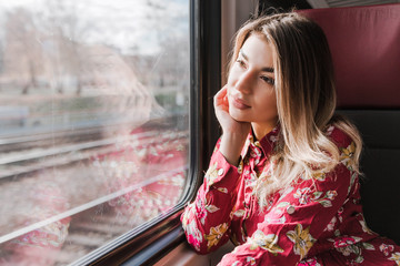 Beautiful girl sitting alone in a train and sadly looks out the window