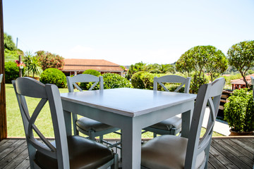White table with chairs on the beauitiful sunny graden view. Terrace with garden landscape. 