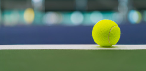 one new tennis ball on white line in blue and green hard court with beautiful bokeh, copy space on...