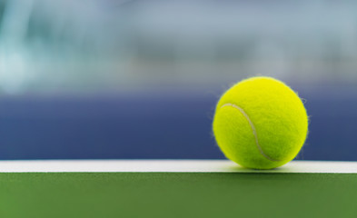 one new tennis ball on white line in blue and green hard court with copy space on left