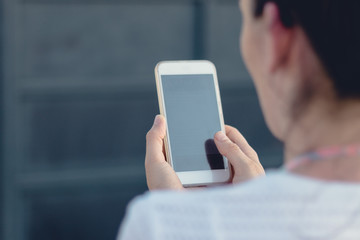 Close view of a young person holding and making use of a mobile phone or smart phone. Blurred background