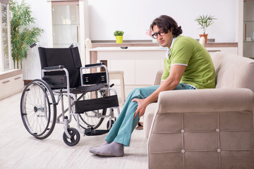 Young male invalid in wheelchair suffering at home