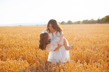 Photo of mother having fun in a field with his daughter, wearing white dress