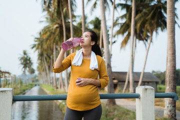thirsty pregnant woman after workout drinking a bottle of water