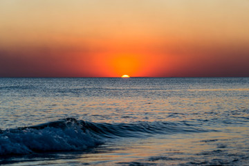 Sea wave against the rays of the setting sun